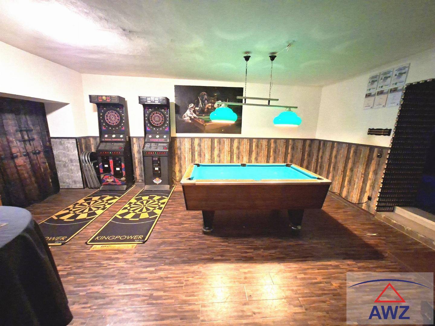 Spielzimmer mit Billardtisch, Dartautomaten und Holzvertäfelung an den Wänden.