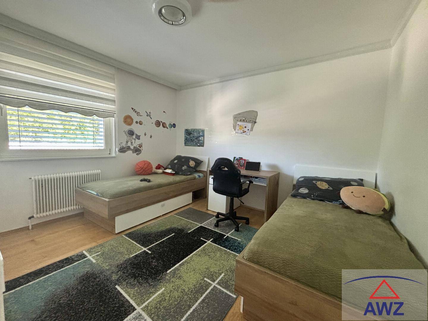 Kinderzimmer mit zwei Einzelbetten, Schreibtisch und hellem Laminatboden.