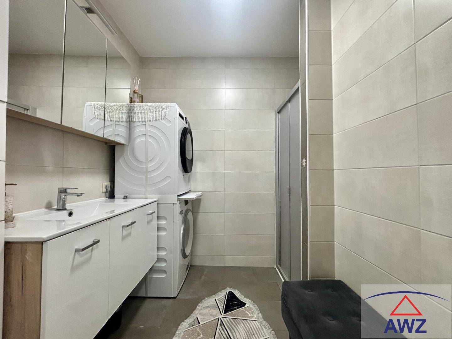 Modernes Badezimmer mit Dusche, Einzelwaschbecken und integrierter Waschmaschine.
