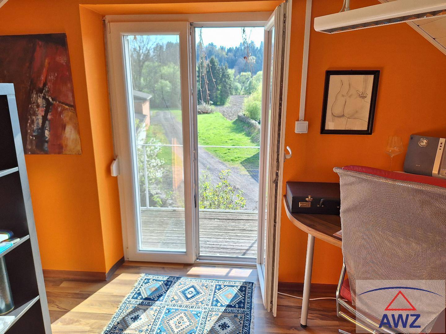Helles Zimmer mit orangefarbenen Wänden, Holzboden und Zugang zu einem Balkon mit Weitblick.