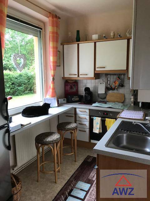 Helle Küche mit Fensterblick ins Grüne, weißen Schränken und einer kleinen Frühstücksbar.