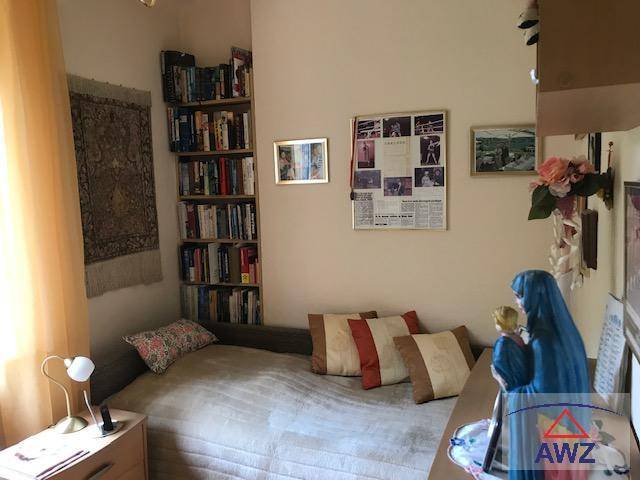 Kleines Schlafzimmer mit Einzelbett, Bücherregal und Fenster für natürliches Licht.