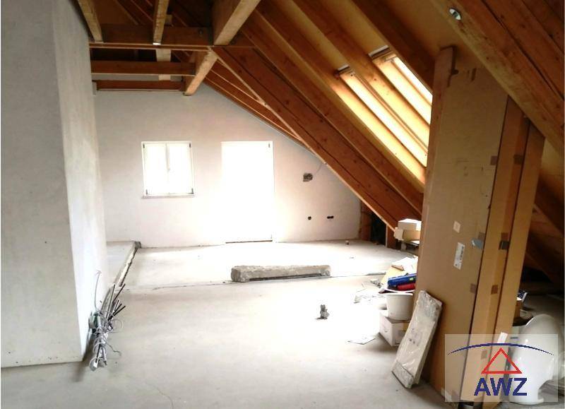 Unausgebauter Dachboden mit sichtbaren Holzbalken, Dachfenstern und Rohbauzustand.