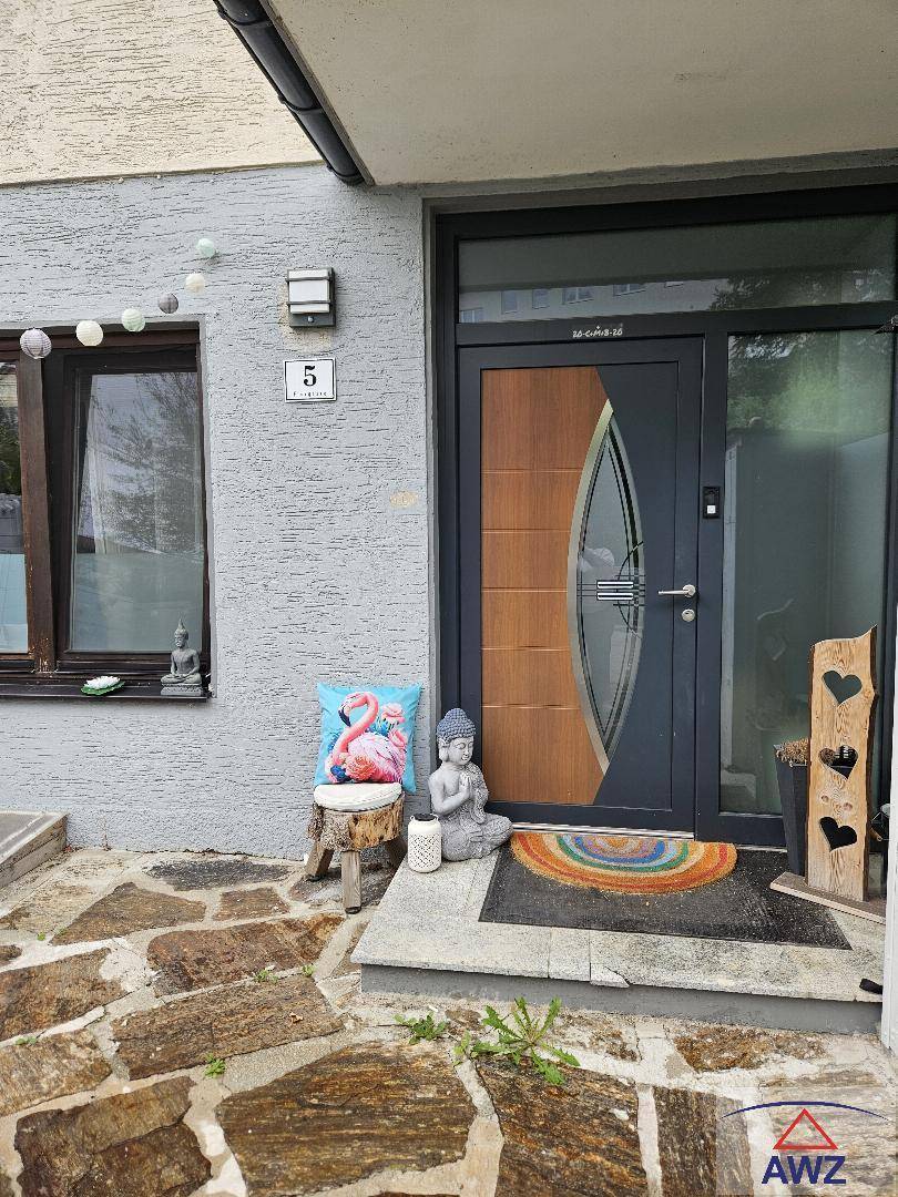 Moderner Hauseingang mit stilvoller Tür, Steinplattenweg und dekorativen Elementen im Vorgarten.