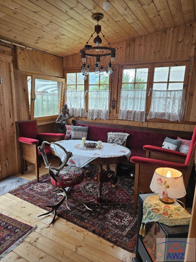 Gemütlicher, holzverkleideter Raum mit traditionellen Möbeln, Fenstern und rustikalem Charme.