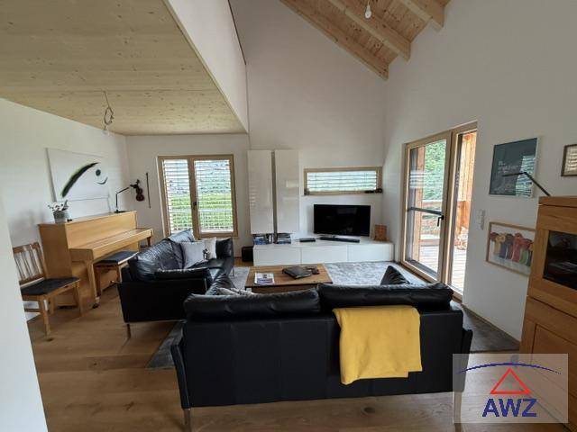 Geräumiges Wohnzimmer mit hohen Holzdecken, bequemen Sofas und Zugang zur Terrasse.