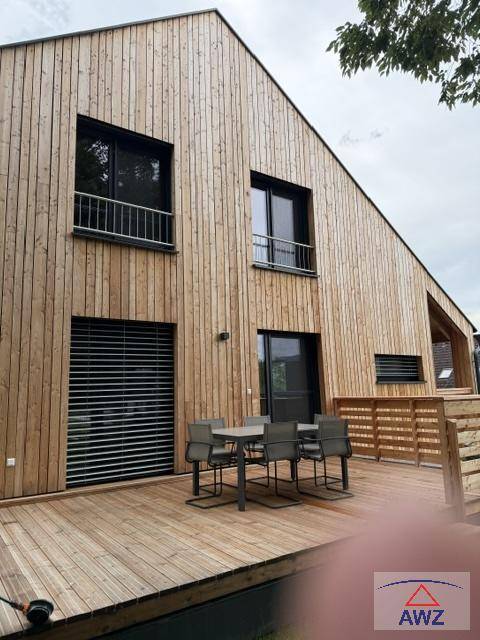 Große Holzterrasse mit Esstisch und Stühlen, ideal für Mahlzeiten im Freien.