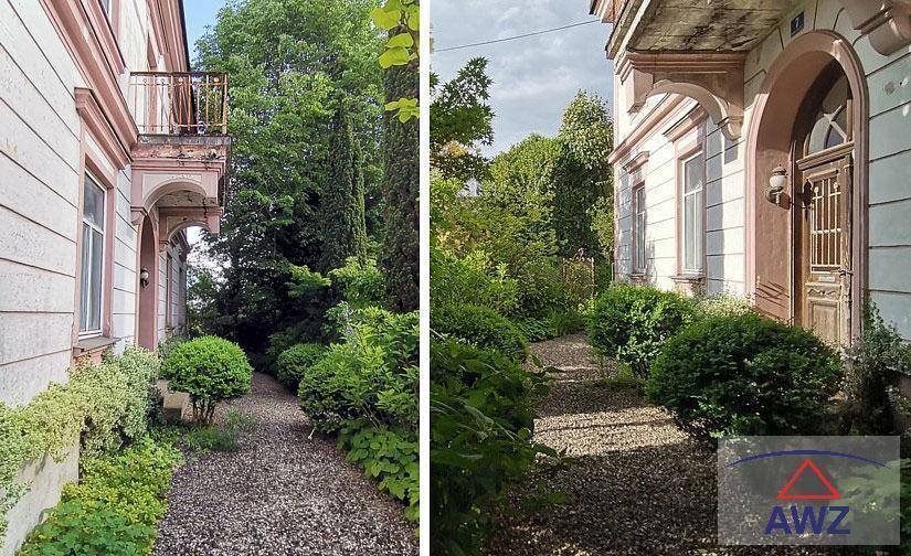 Historische Gebäudefassade mit üppiger Vegetation und einem Kiesweg im Gartenbereich.