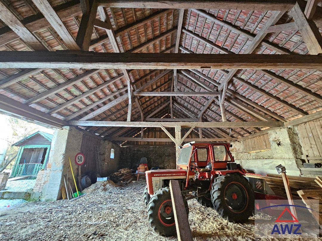 Große Scheune mit beeindruckender Holzkonstruktion des Daches und einem geparkten Traktor.