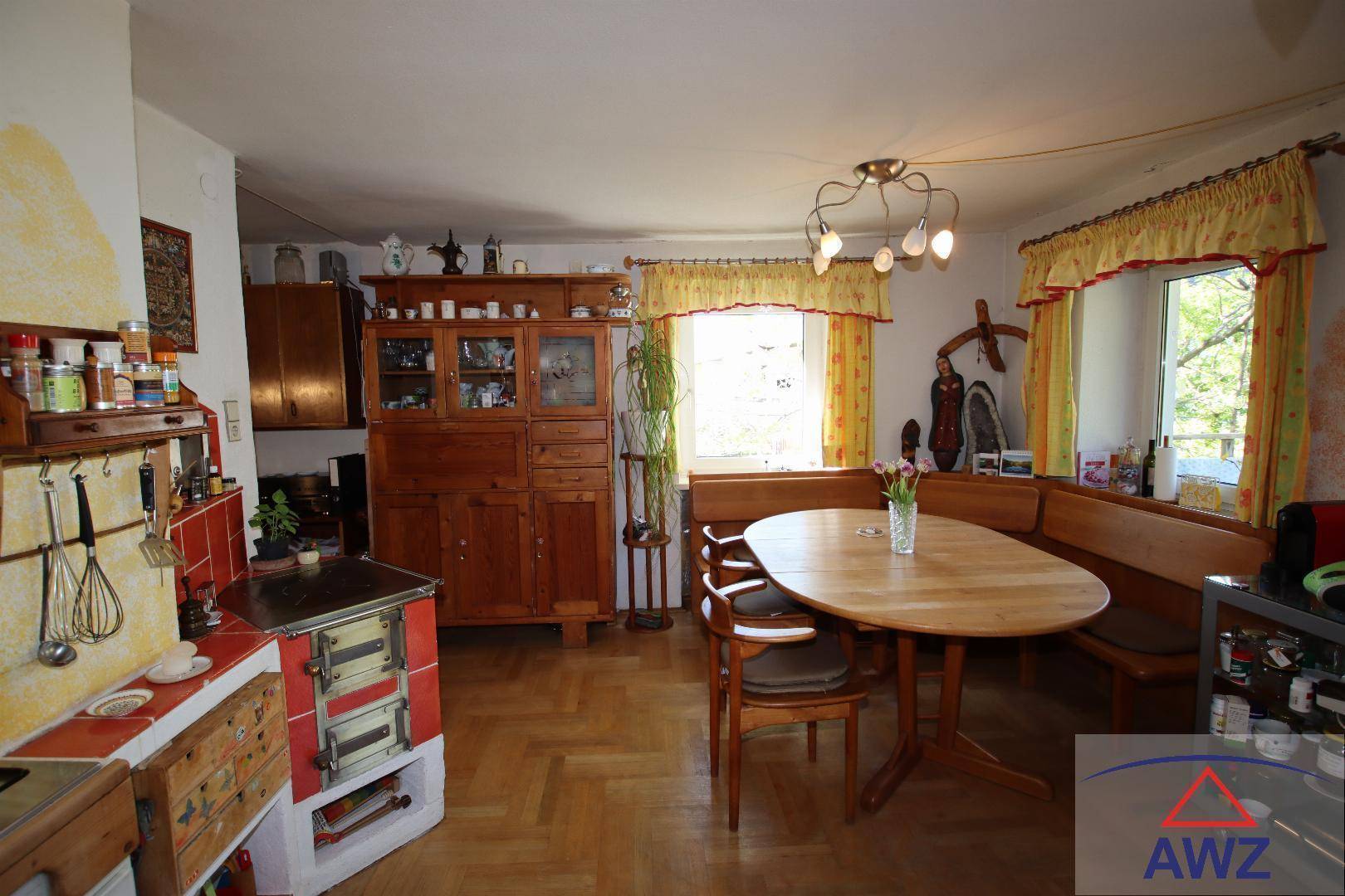 Gemütliche Wohnküche im Landhausstil mit traditionellem Kachelofen und Holzboden.