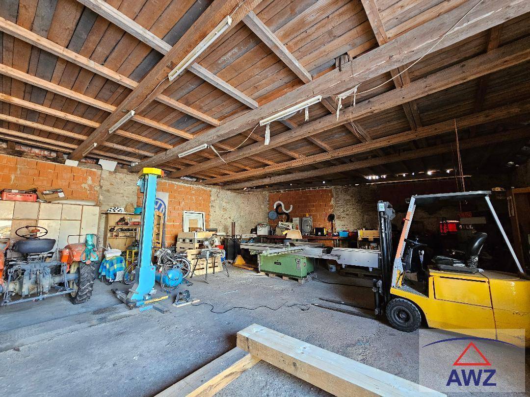 Geräumiger Werkstattbereich mit freiliegenden Holzbalken, Ziegelwänden und verschiedenen Maschinen.