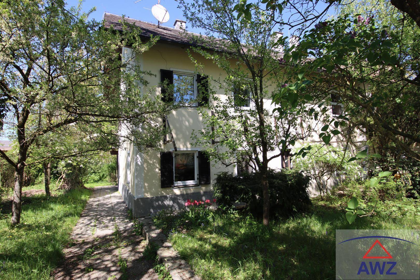 Charmantes Einfamilienhaus umgeben von üppigem Grün und altem Baumbestand.