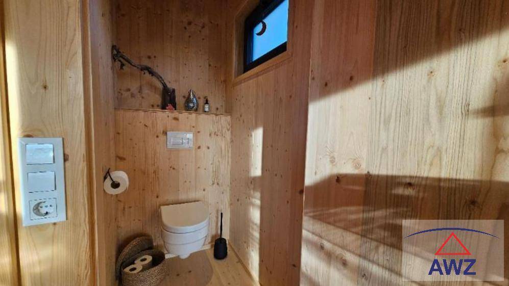 Separate Toilette mit Holzwänden und einem kleinen Fenster für natürliche Belüftung.