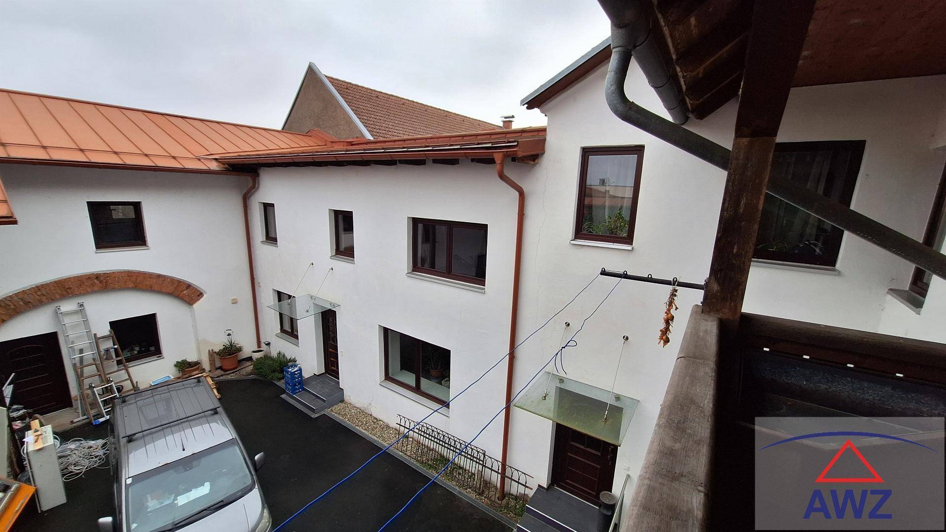 Blick von oben auf die weiße Hausfassade mit braunen Fenstern und dem Innenhof.