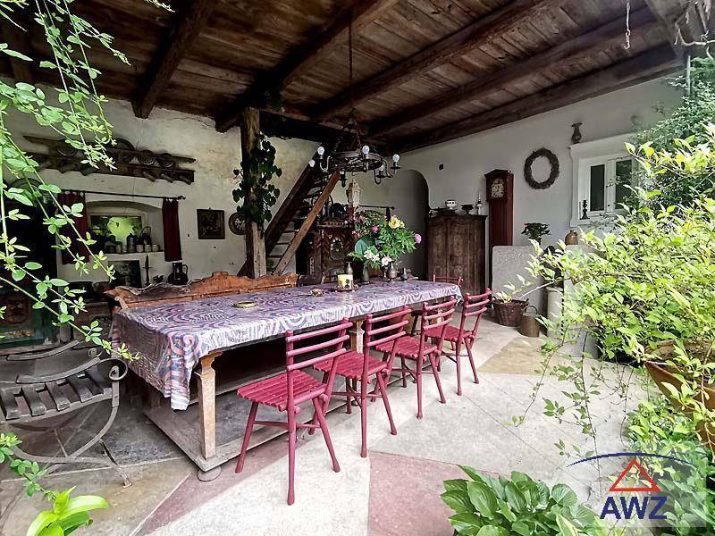 Überdachte Terrasse mit großem Esstisch, Holzbalkendecke und vielen Pflanzen.