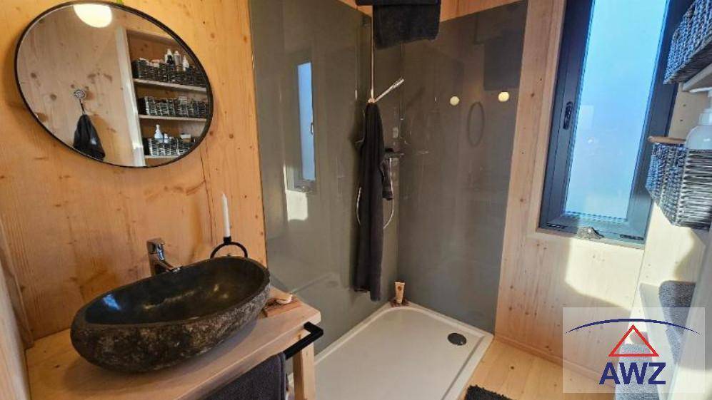 Modernes Badezimmer mit Holzwänden, Steinswaschbecken und einer Duschkabine mit Fenster.