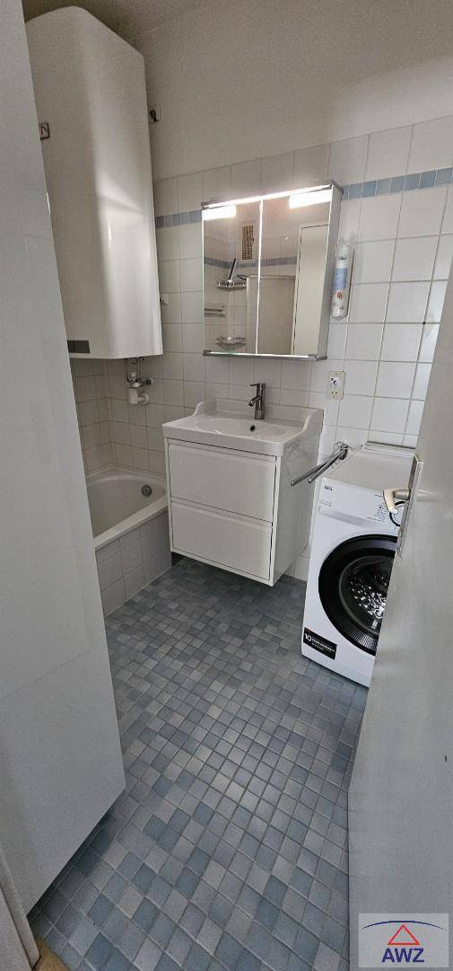 Funktionales Badezimmer mit Badewanne, Waschbecken, Spiegelschrank und Waschmaschine.