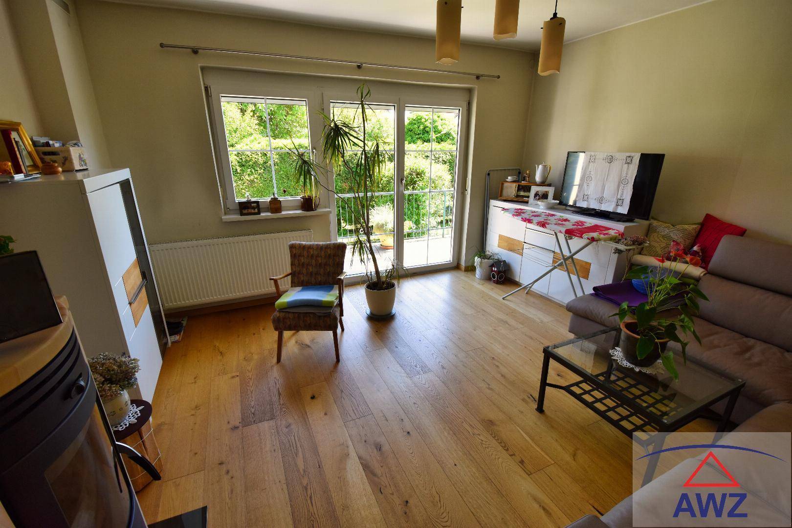 Helles Wohnzimmer mit Holzboden, großen Fenstern und Zugang zum Garten.