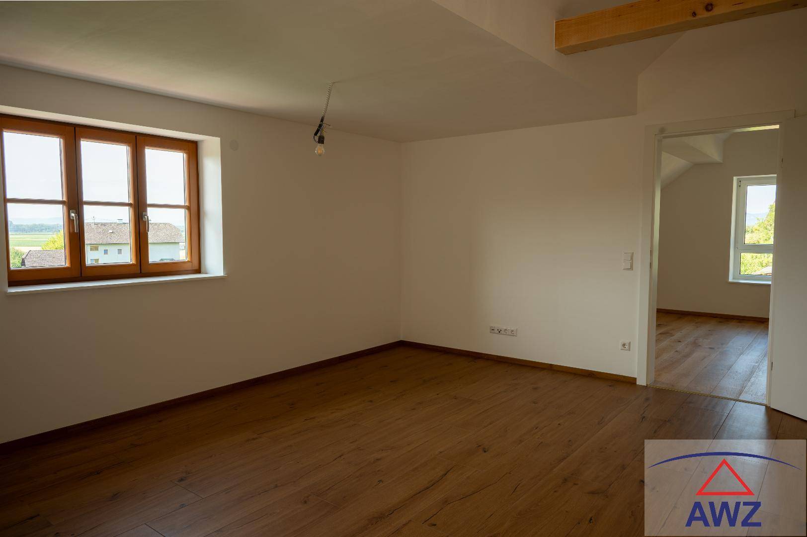 Heller Raum mit Parkettboden und Fenster mit Blick ins Grüne, ideal für ein Schlafzimmer.