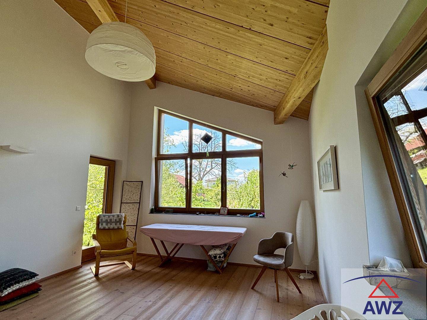 Heller Raum mit hohen Holzdecken, großen Fenstern und viel Tageslicht, ideal als flexibler Wohnbereich.