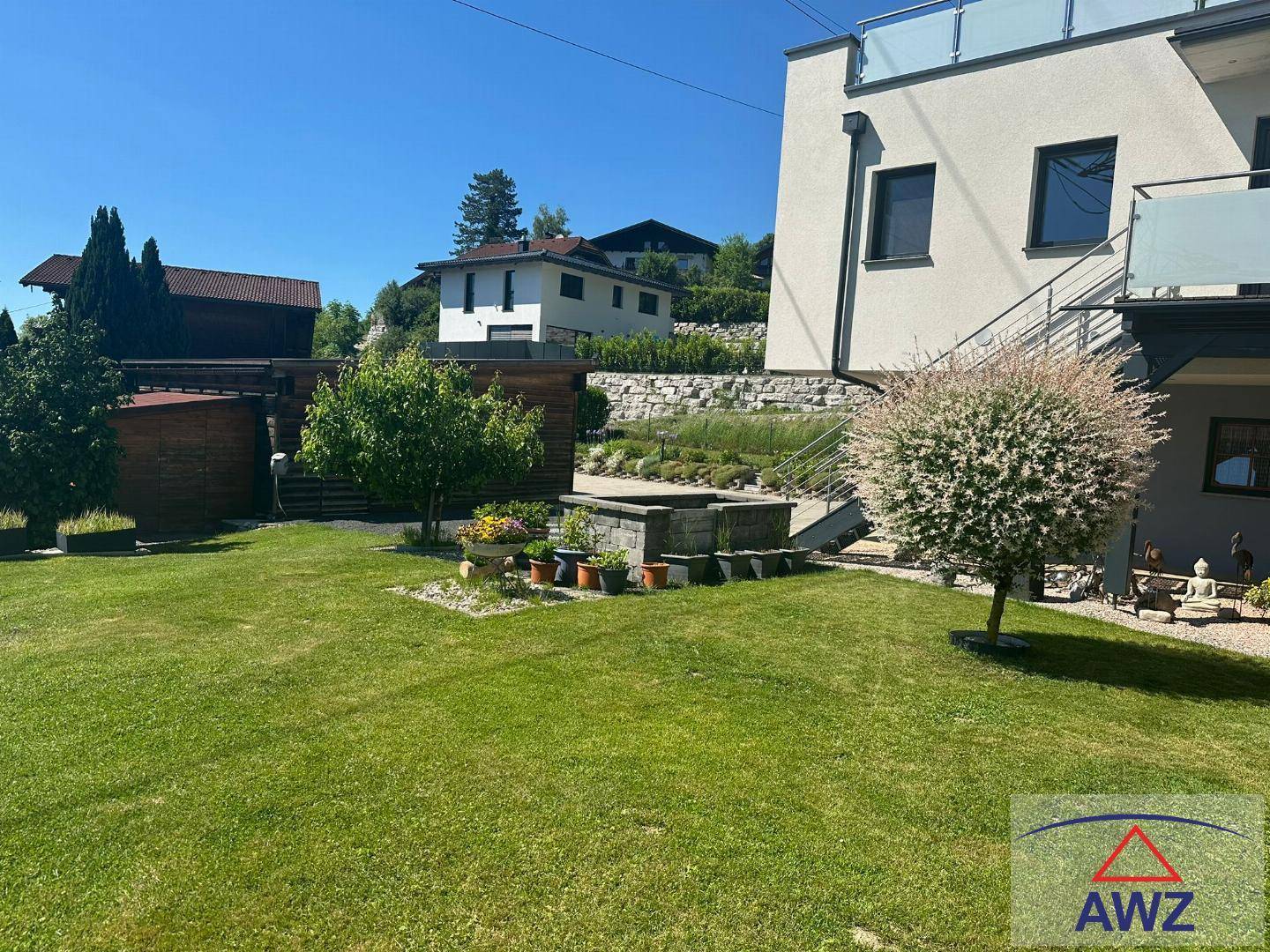Gepflegter Gartenbereich mit Rasenfläche, Zierbaum und Blick auf die umliegenden Häuser.