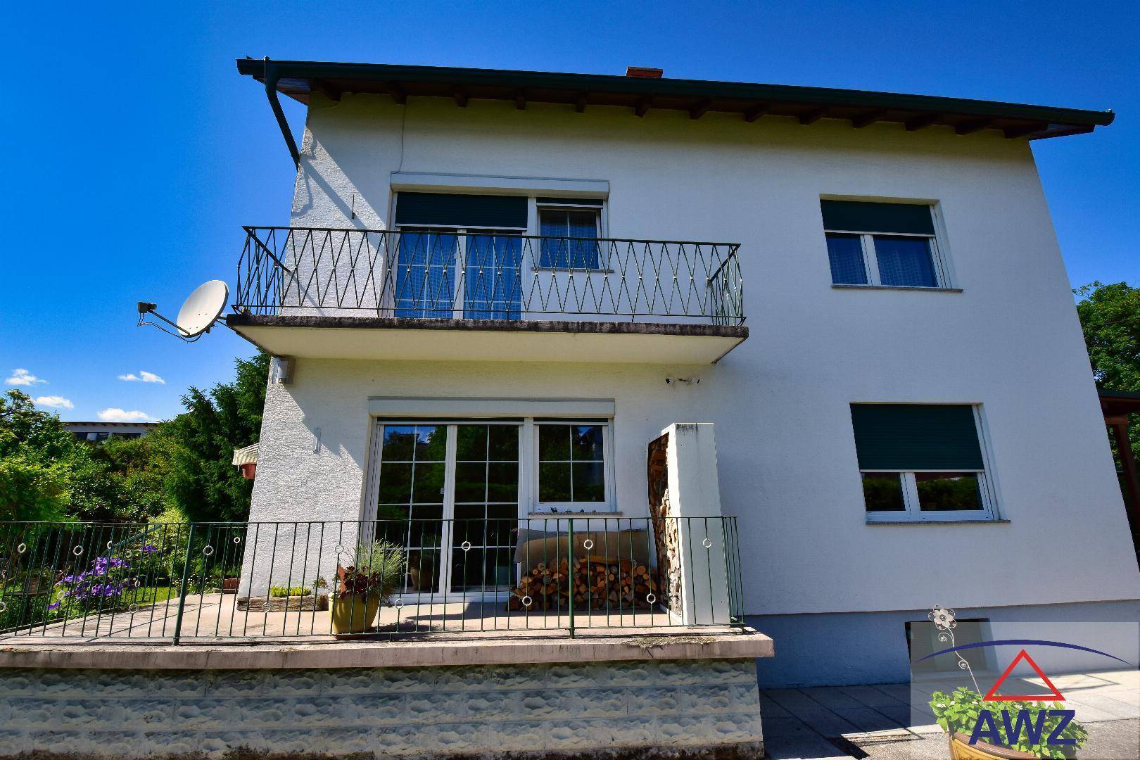 Balkon und Terrasse am Haus mit Blick ins Grüne und Holzstapel.