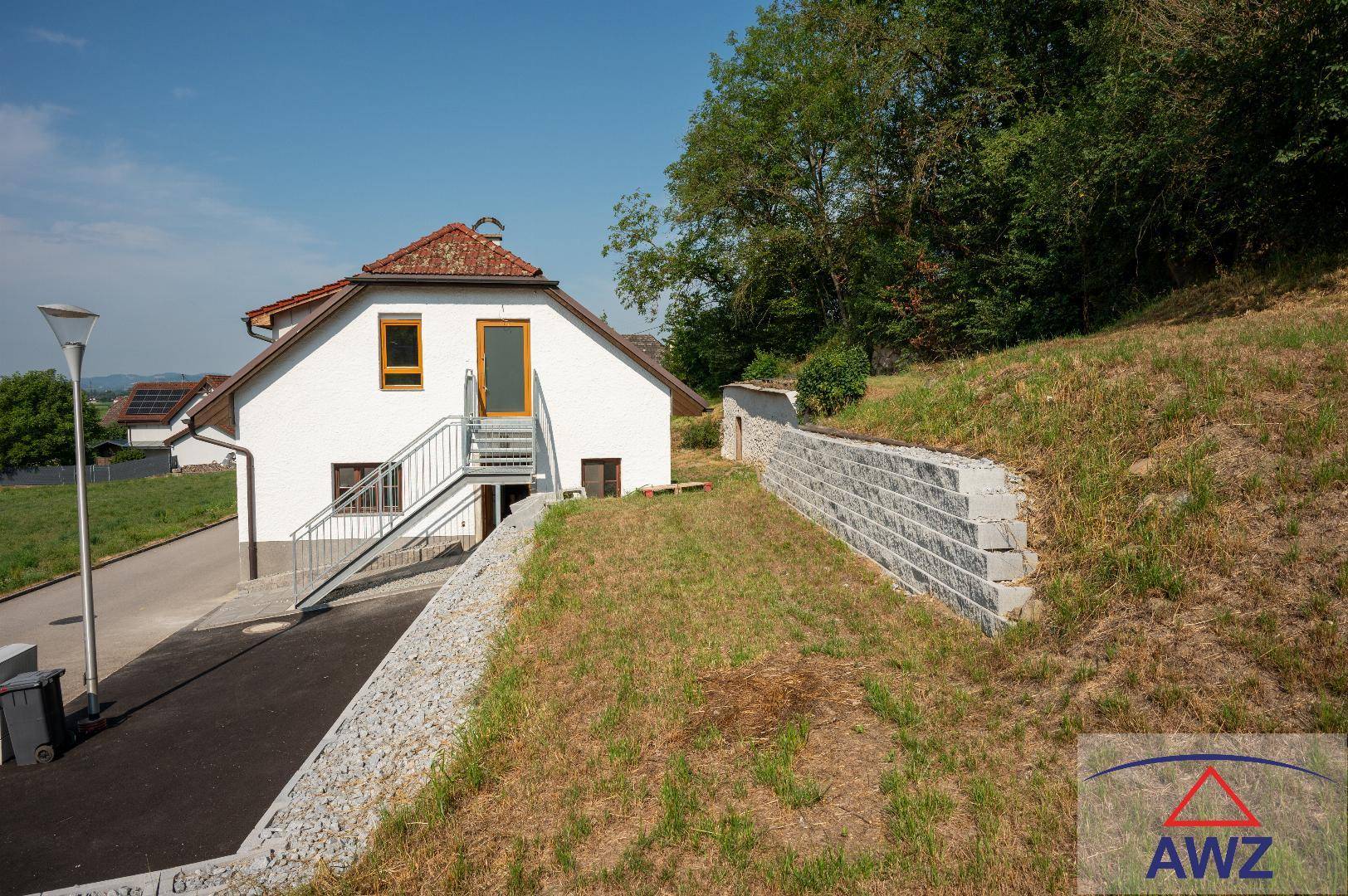 Außenansicht des Hauses mit Hanglage, Stützmauer und Blick auf die Umgebung.