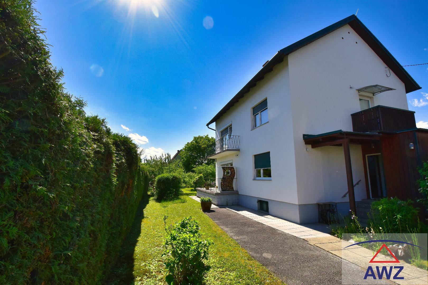Vorderansicht des Hauses mit gepflegter Hecke, Einfahrt und sonnigem Wetter.