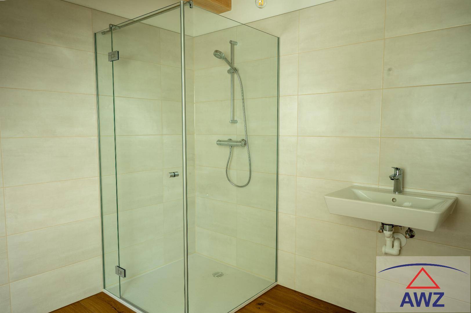 Modernes Badezimmer mit Duschkabine aus Glas, hellen Fliesen und Einzelwaschbecken.
