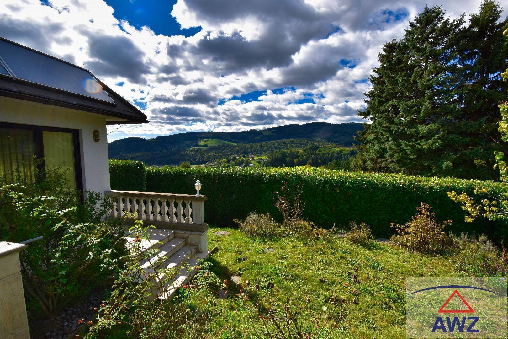 Weitläufiger Blick über die grüne Landschaft und bewaldete Hügel von der Terrasse des Hauses.