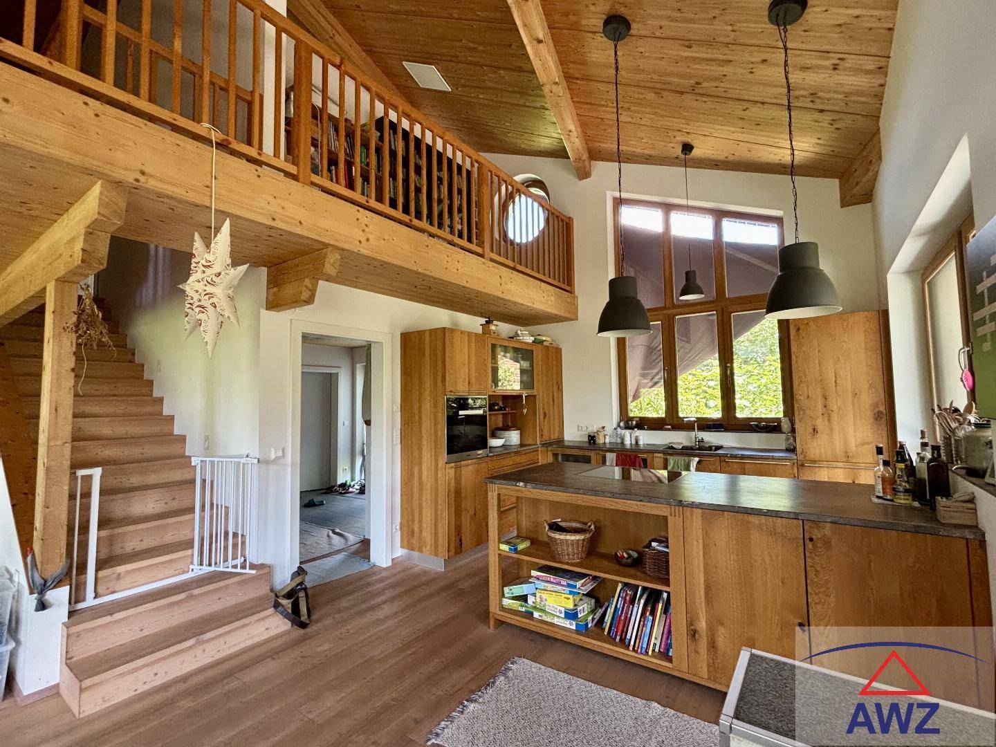 Moderne Holzküche mit Kochinsel und offenem Zugang zu einem Galeriebereich mit hohen Decken.