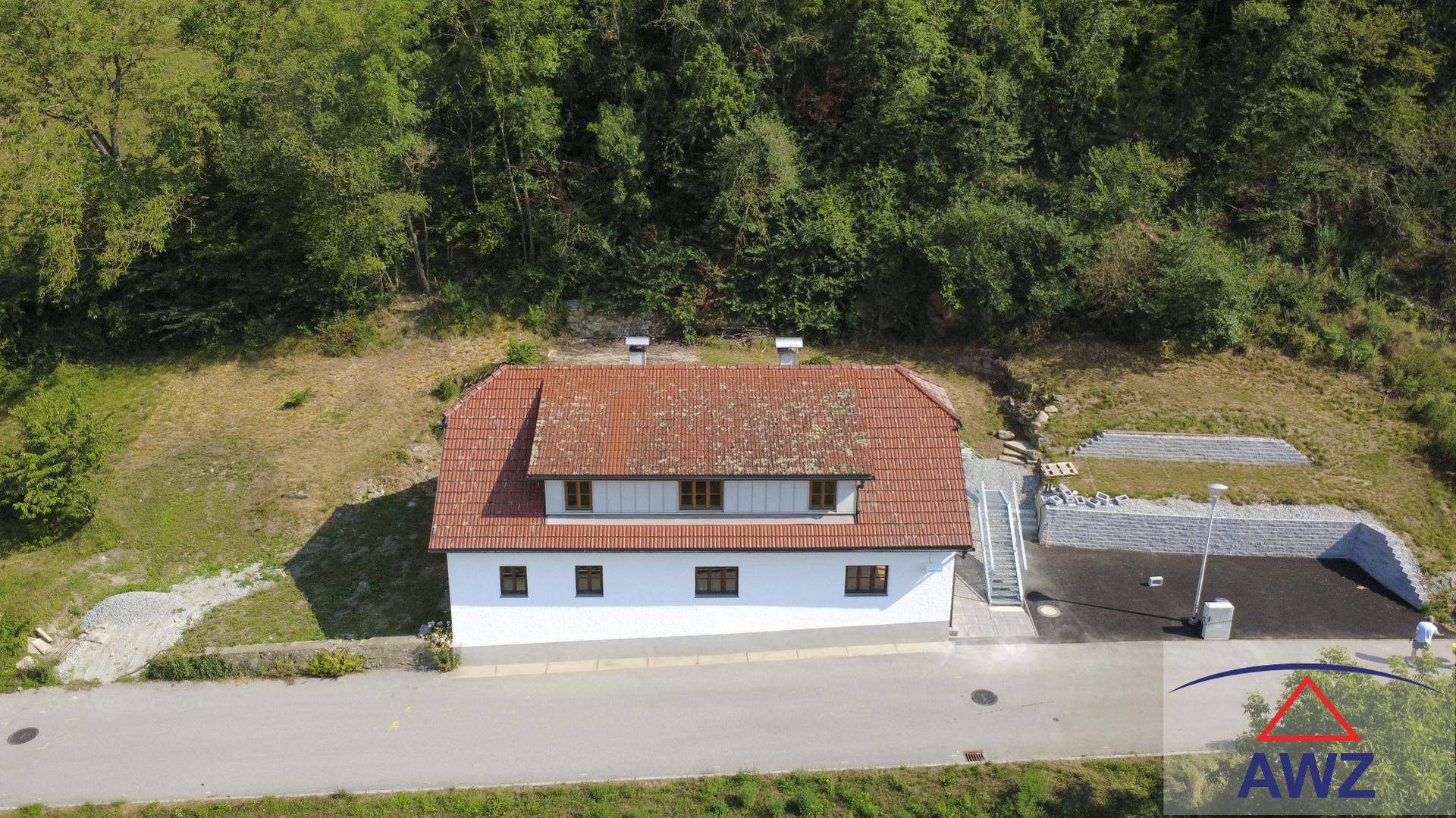 Luftaufnahme eines Hauses mit rotem Ziegeldach, umgeben von viel Grün.