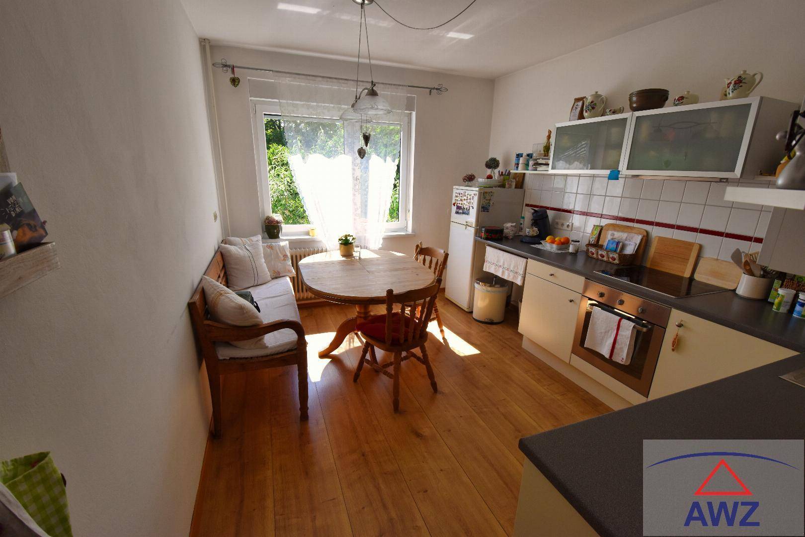 Gemütliche Wohnküche mit Holzboden, Esstisch und Fenster zum Garten.