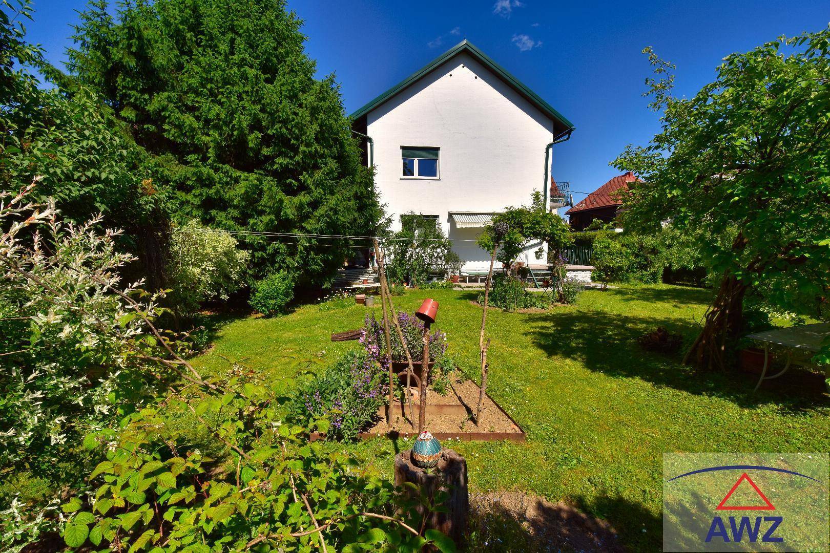 Großer, gepflegter Garten mit Rasenfläche, Bäumen und Blick auf das Haus.