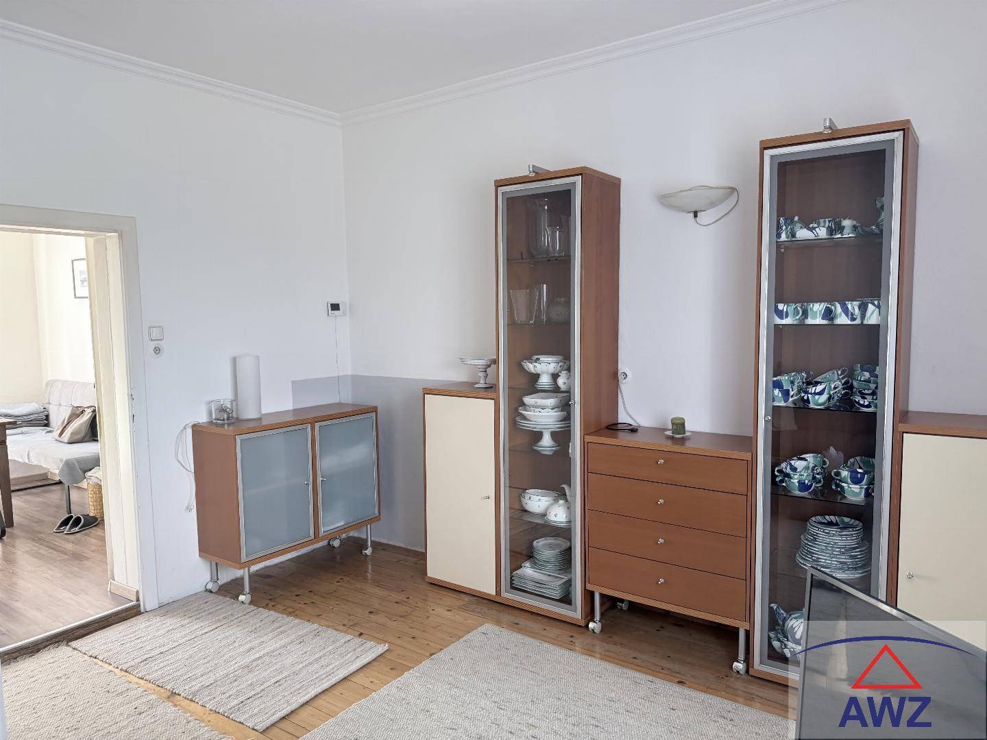 Heller Wohnbereich mit Holzparkettboden und mehreren Vitrinenschränken, der zum Entspannen einlädt.