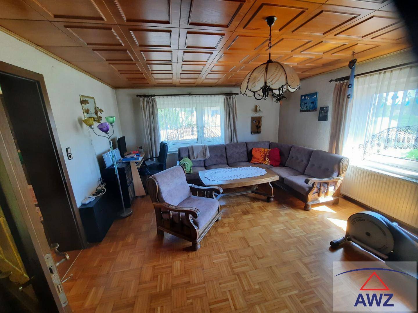Gemütliches Wohnzimmer mit Holzkassettendecke, Parkettboden und großem Sofa.