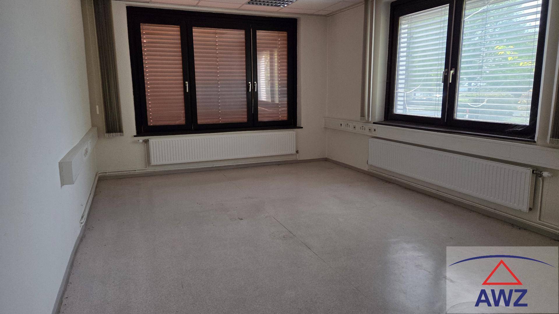 Leerer Raum mit großen Fenstern, Heizkörpern und hellem Bodenbelag, ideal als Büro.