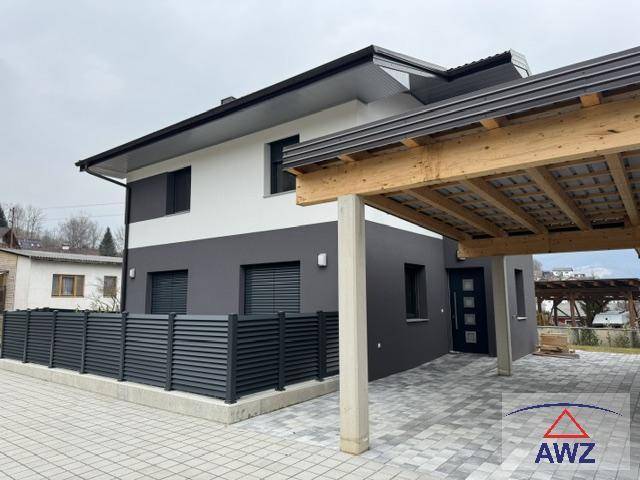 Neubau-Einfamilienhaus mit modernem Carport und gepflasterter Zufahrt.