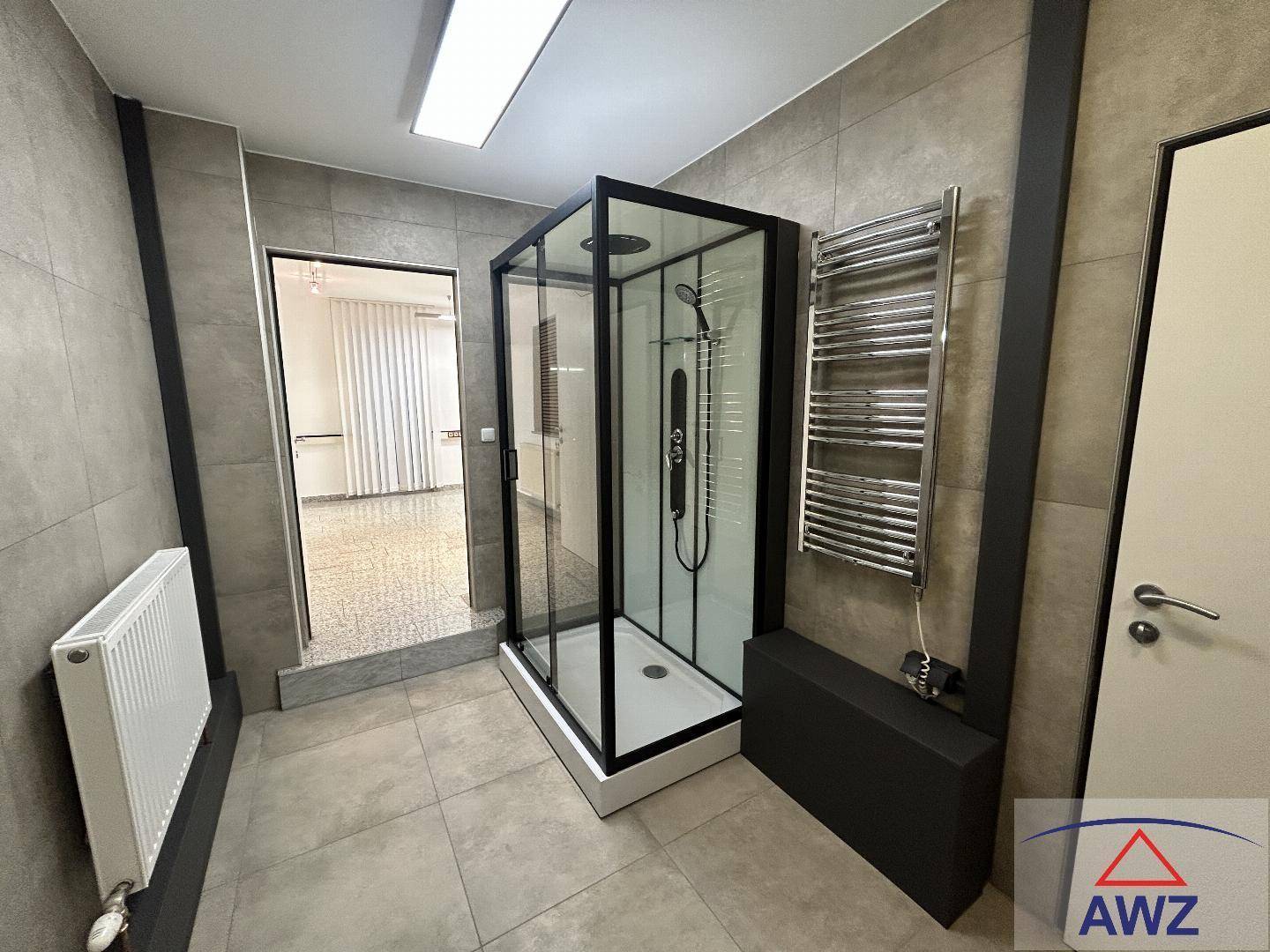 Modernes Badezimmer mit Duschkabine, grauen Fliesen und beheiztem Handtuchhalter.