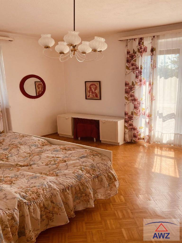 Gemütliches Schlafzimmer mit Doppelbett, floralen Vorhängen und hellem Parkettboden.