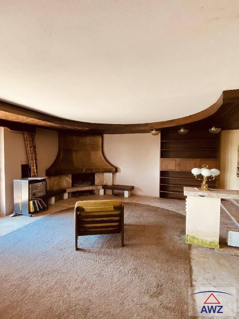 Geräumiges Wohnzimmer mit großem Kamin, Teppichboden und integrierten Regalen.