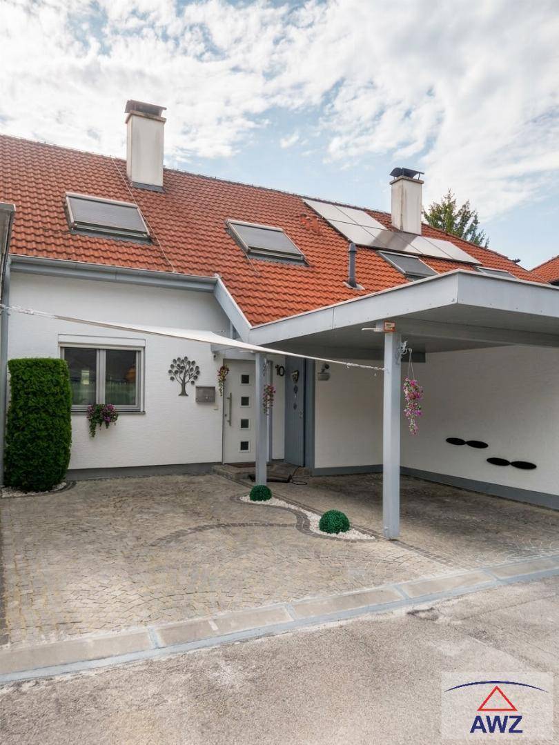 Reihenhausfassade mit Carport, gepflasterter Einfahrt und Solarpaneelen auf dem Dach.