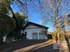 Doppelgarage mit zwei Toren und gepflasterter Zufahrt, umgeben von Bäumen.