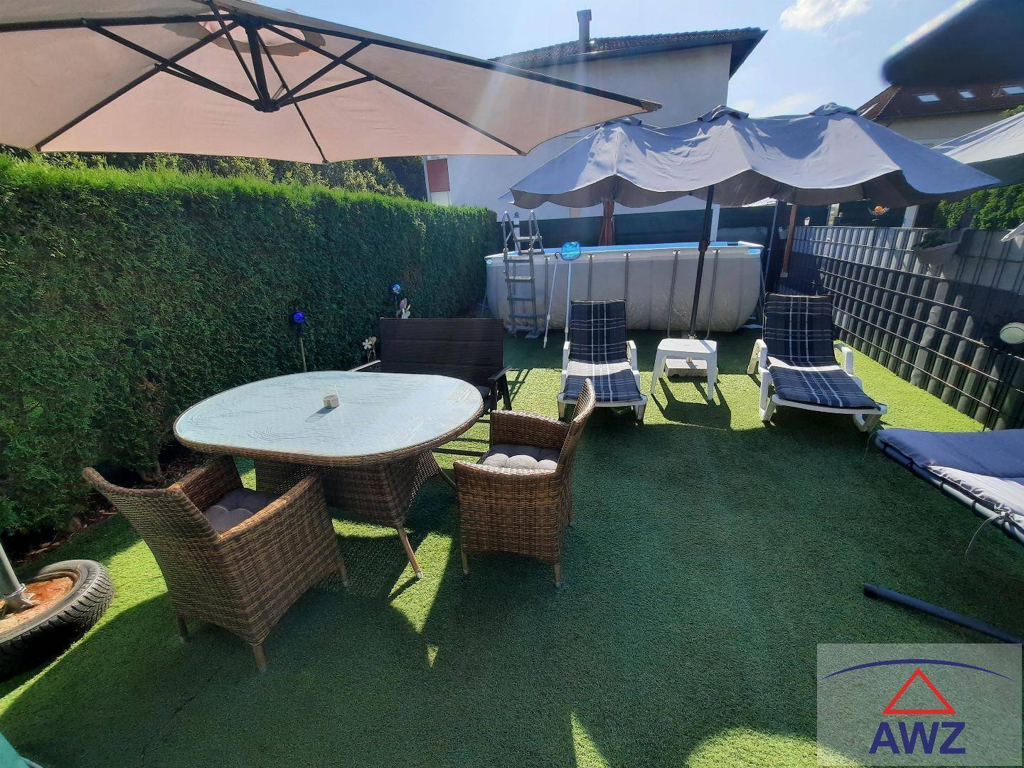 Sonniger Gartenbereich mit Sitzgelegenheiten, Sonnenschirmen und einem Aufstellpool.