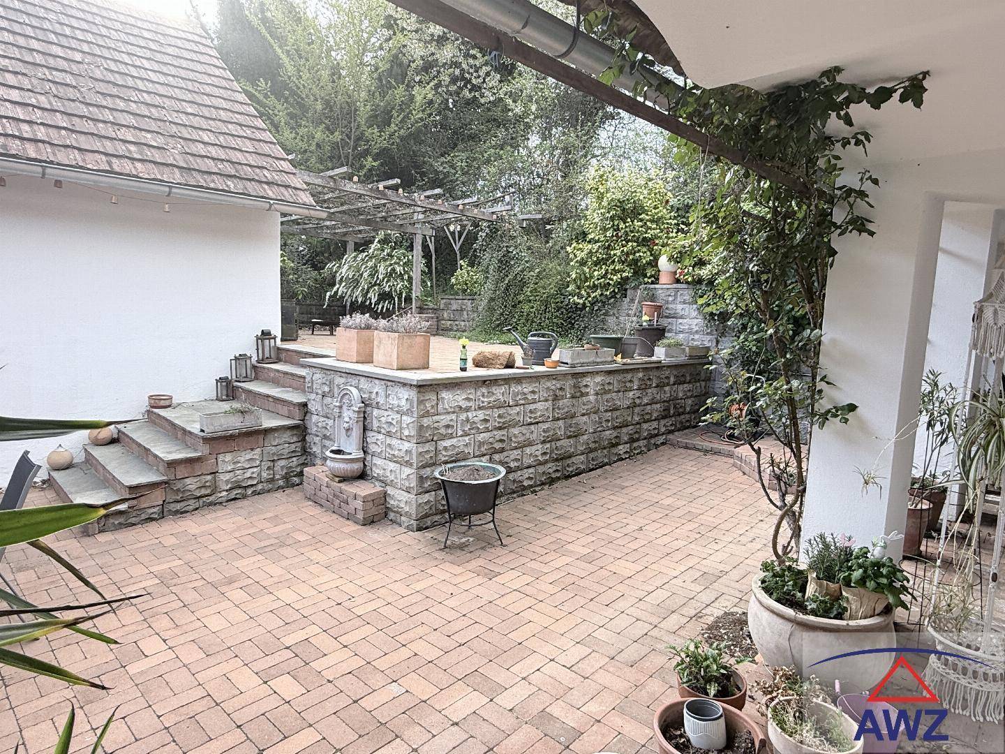 Gemütliche gepflasterte Terrasse mit Steinstufen und Pflanzen, ideal für entspannte Stunden im Freien.