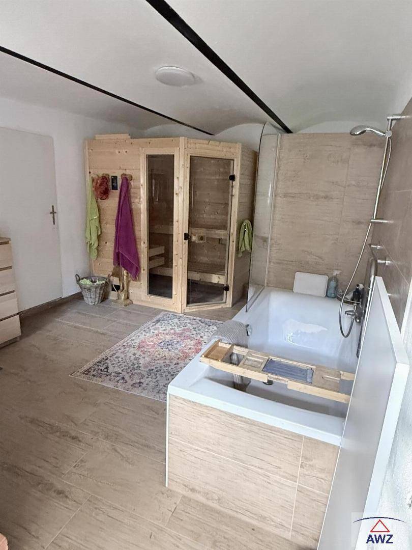 Modernes Badezimmer mit Badewanne, begehbarer Dusche und integrierter Sauna für Wellnessmomente.