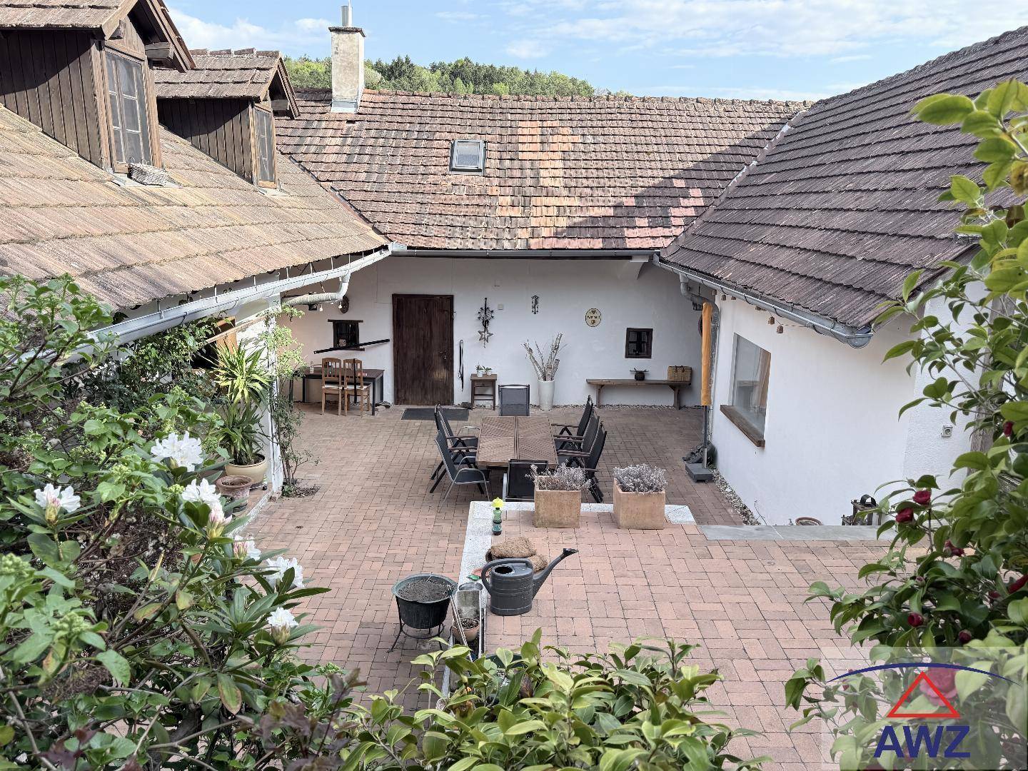 Idyllischer Innenhof mit gepflastertem Boden und Gartenmöbeln, umgeben von traditionellen Gebäuden.