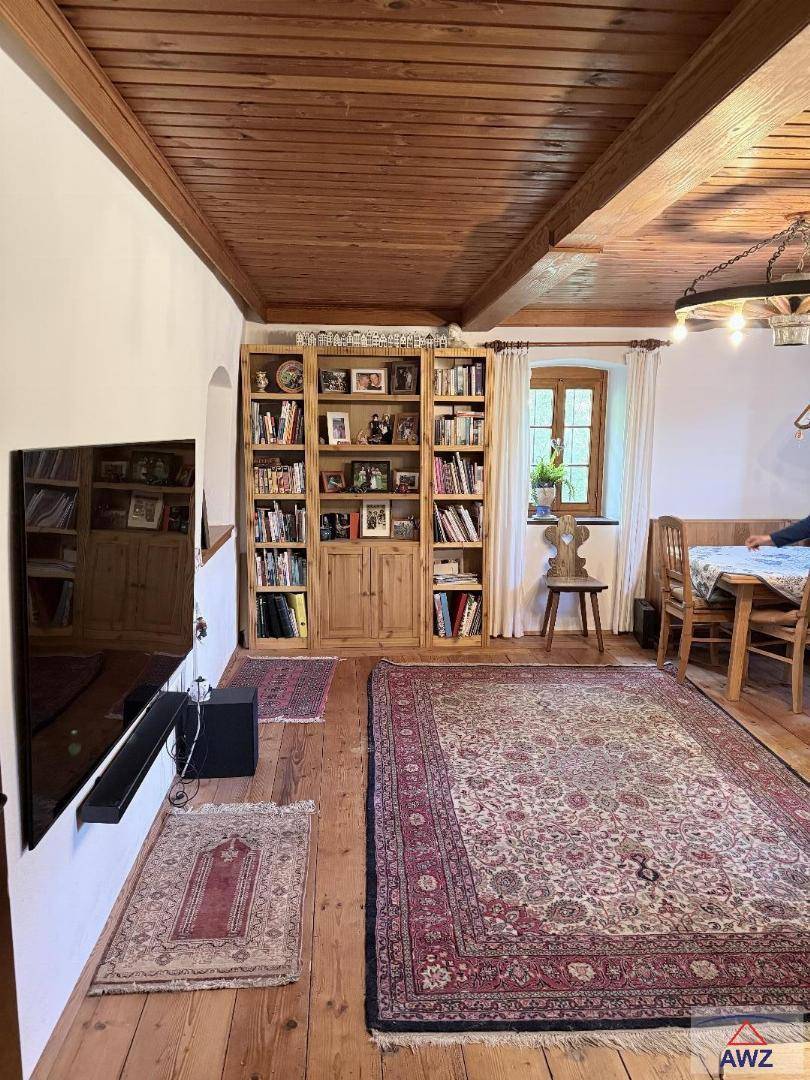 Traditioneller Wohn- und Essbereich mit Holzboden, Bücherregal und rustikalen Möbeln.