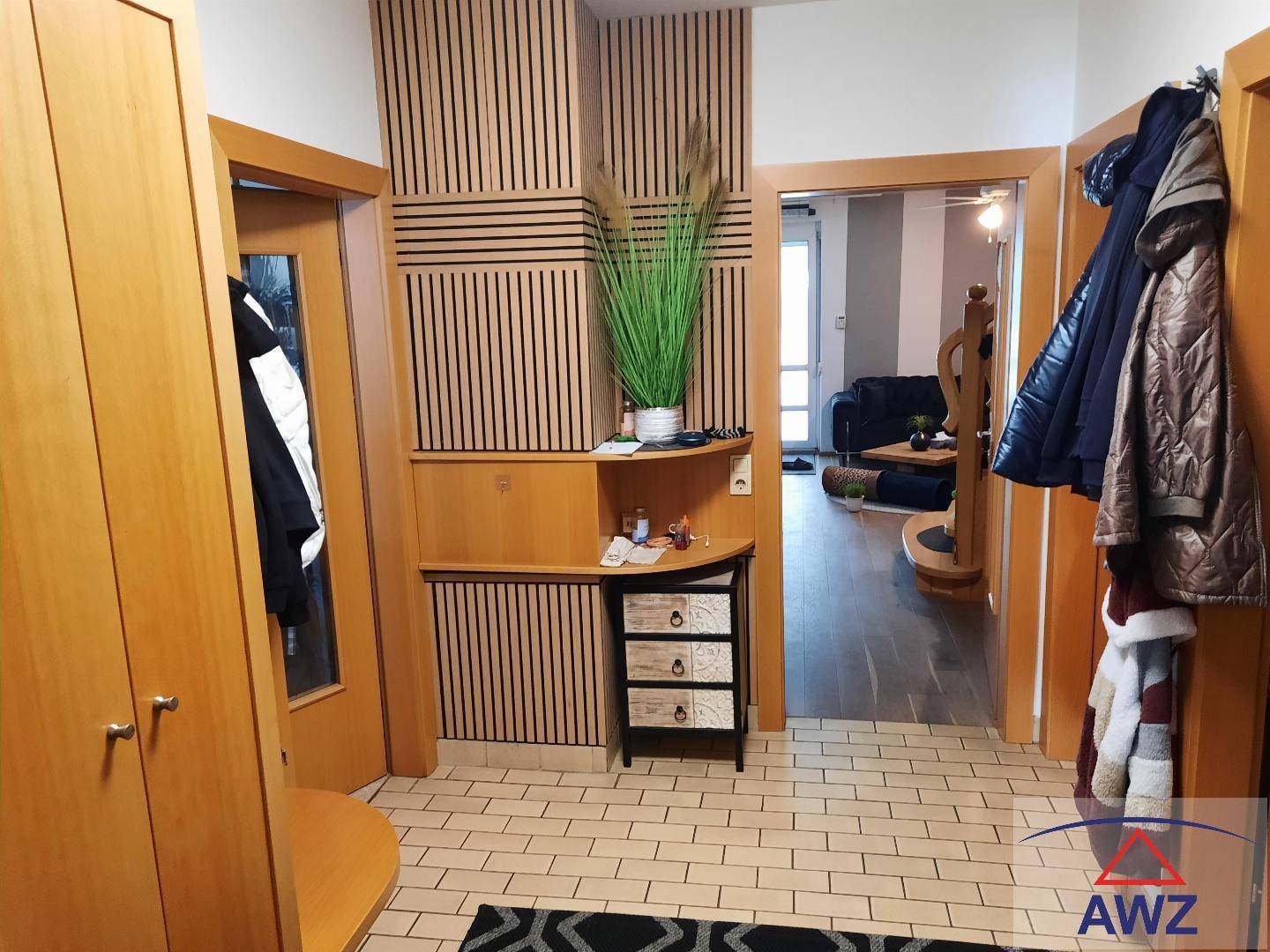 Heller Eingangsbereich mit Holzmöbeln, vertikalen Holzpaneelen und Fliesenboden.