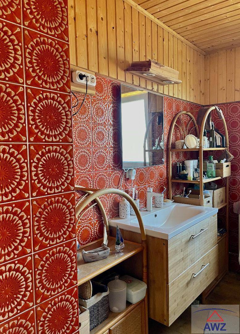 Badezimmer mit auffälligen rot-weißen Fliesen, Holzverkleidung und einem Waschbecken mit Unterschrank.